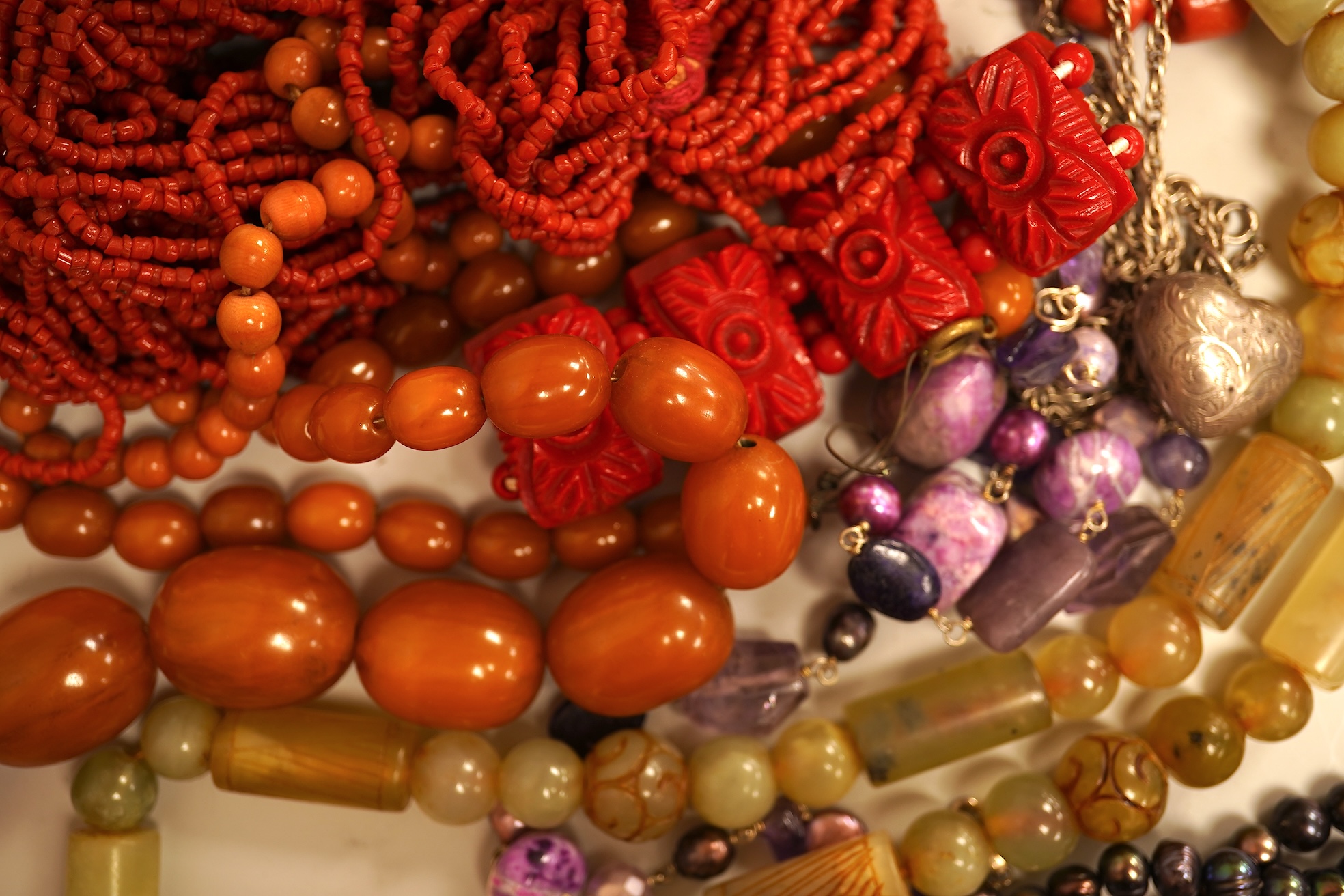 A small group of sundry jewellery including a simulated amber necklace and a multi strand coral bead necklace, etc.